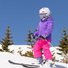 a child skiing on a mountain wearing a purple quilted jacket