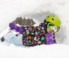 Child in flower printed jacket lying in the snow