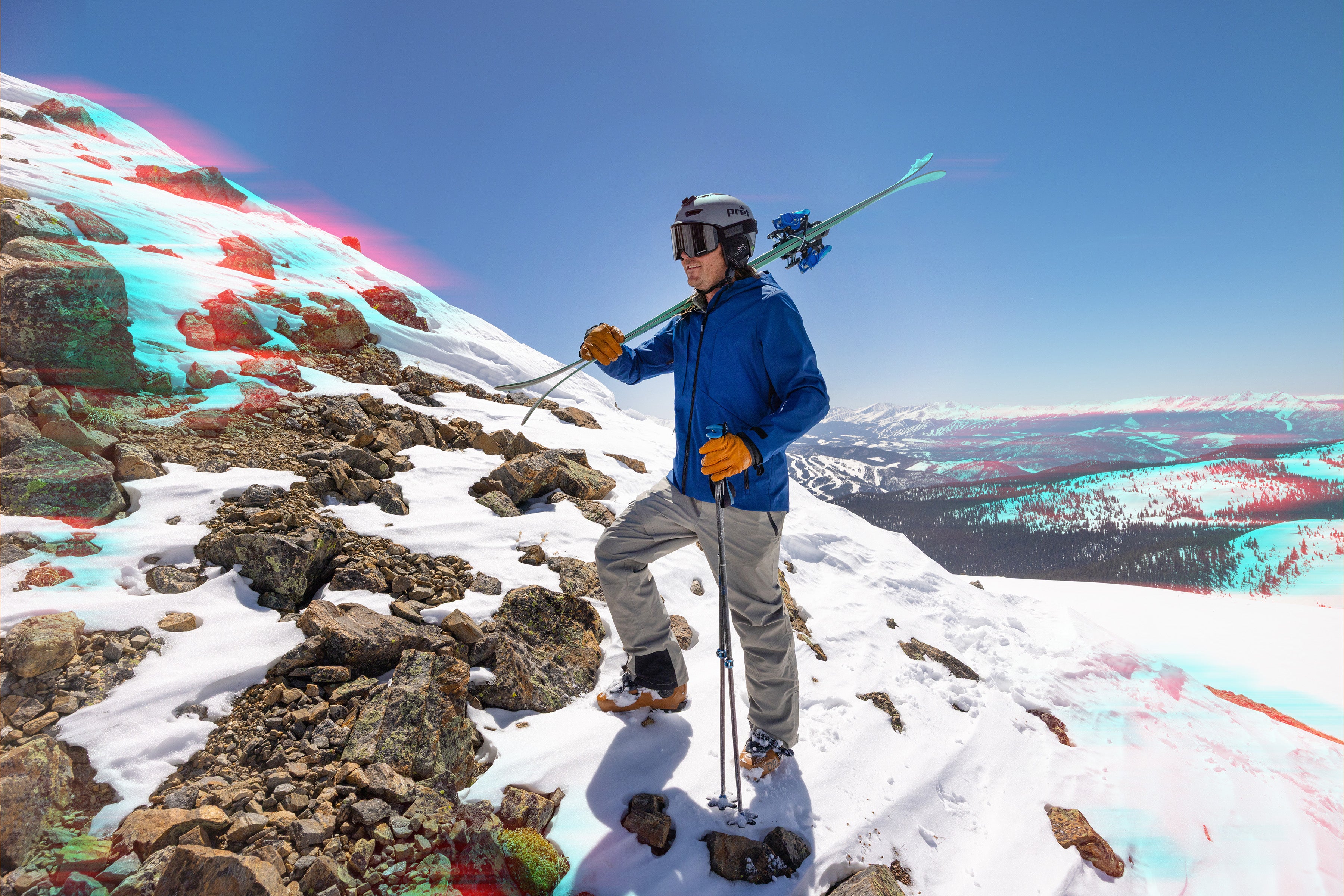 Man with skis and poles on a snowy ad rocky mountain peak