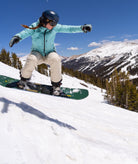 Person snowboarding on a snowy mountain with a clear blue sky